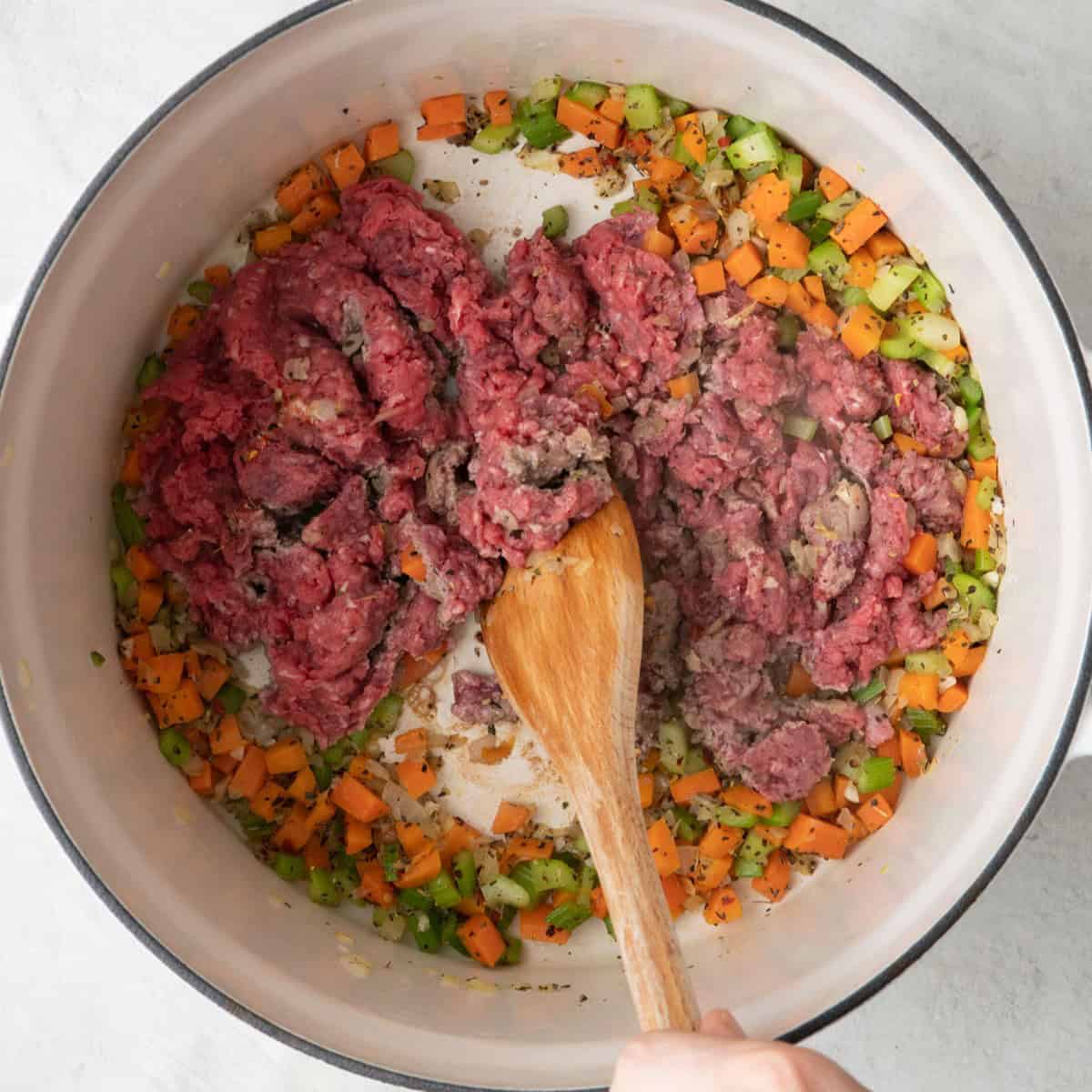 Ground beef added and breaking up partially cooked pieces with a spatula.