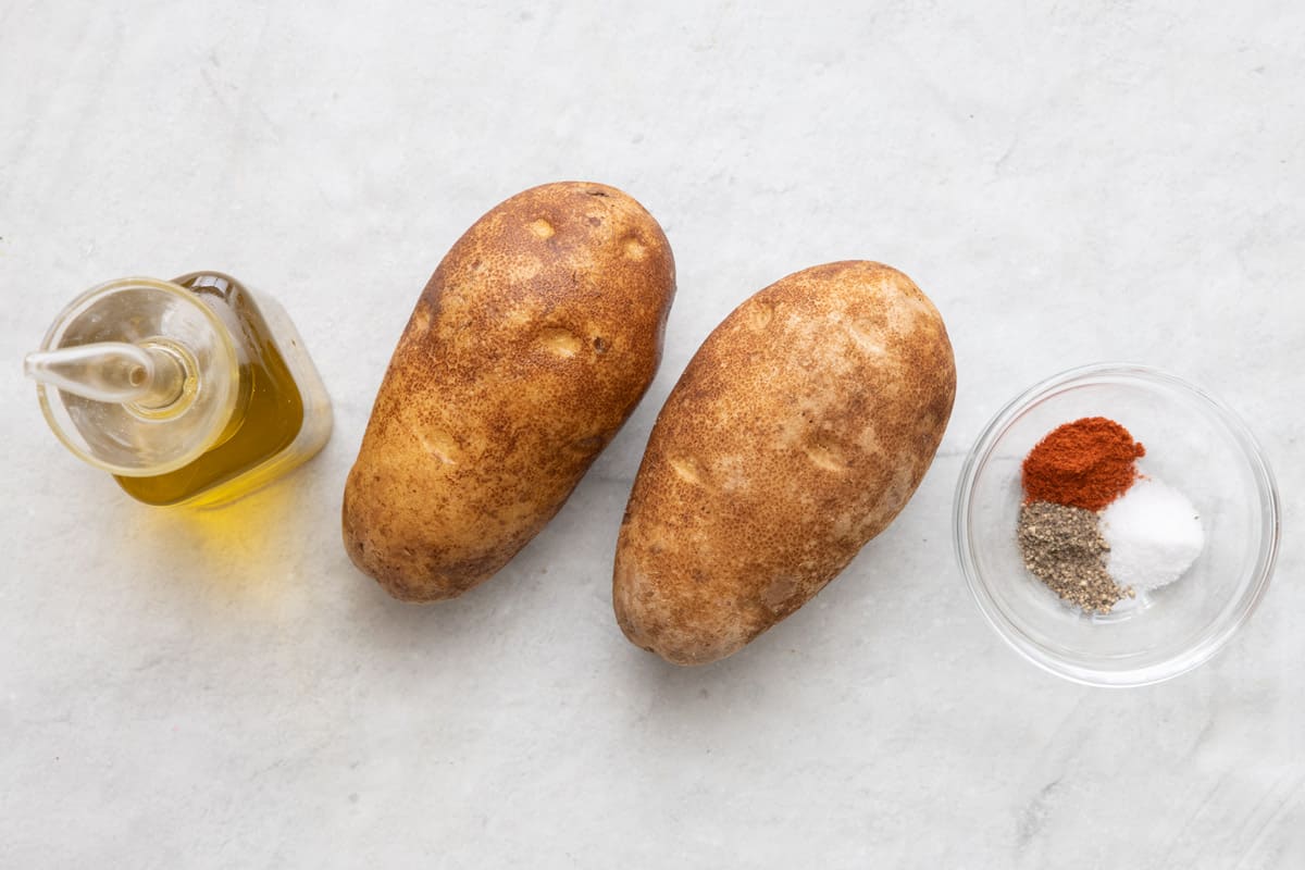 Ingredients before prepped: oil, 2 potatoes, and spices in a small dish.