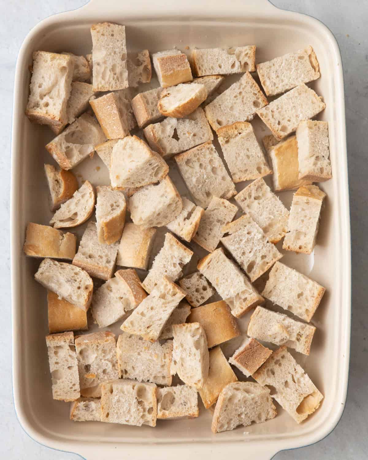 Bread cubes in oiled baking dish.