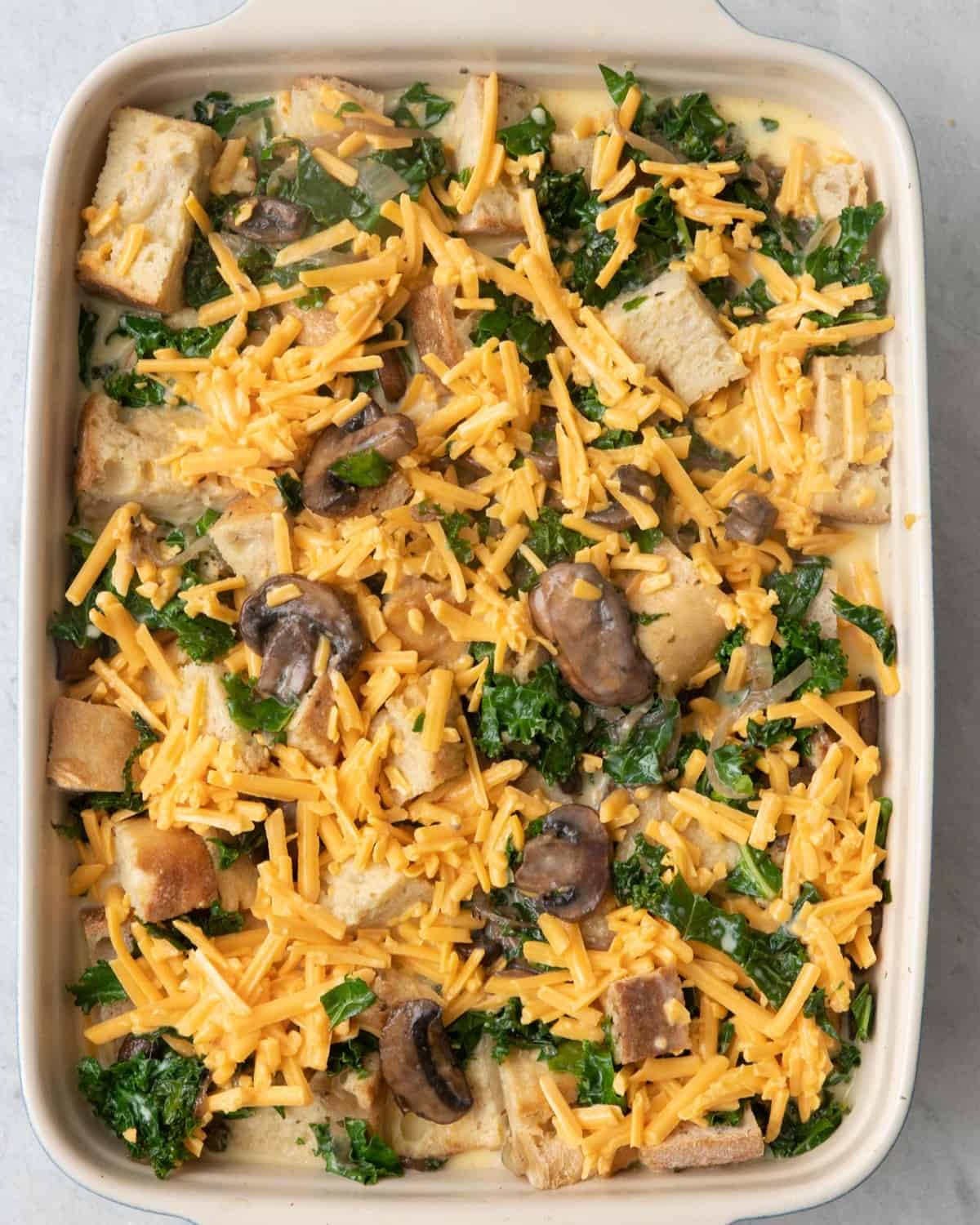 Strata with shredded cheese on top before baked.