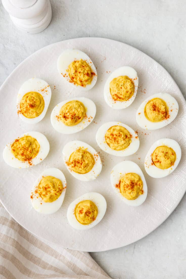 Plate with 12 deviled eggs sprinkled with paprika.