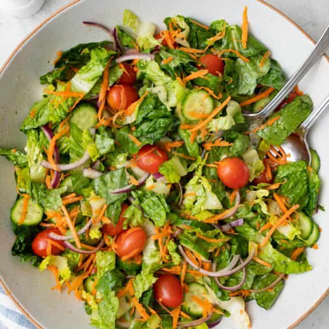 Everyday garden salad tossed with tomatoes, carrots, cucumbers, and shredded carrots.