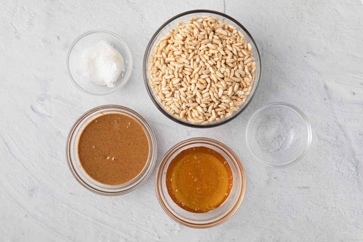 Ingredients for recipe in individual bowls: coconut oil, almond butter, brown rice cereal, honey, and salt.