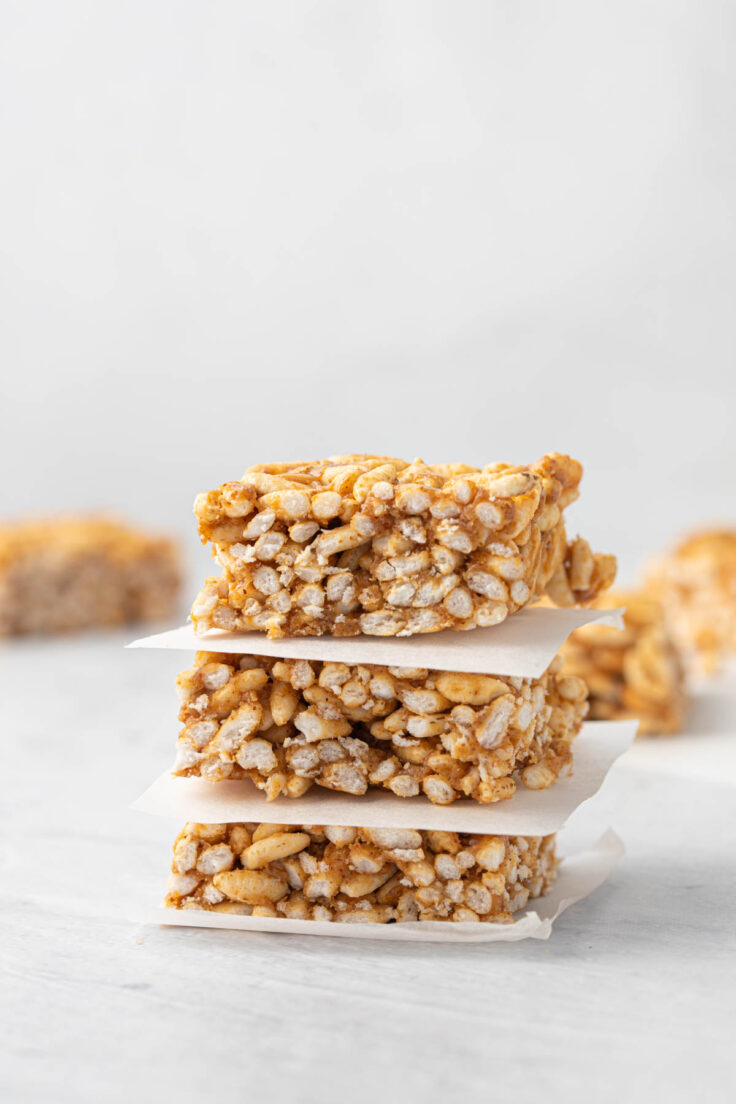 3 rice Krispie treats stacked on top of each other with a small square of parchment paper between each square.