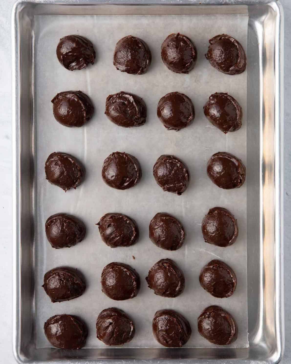 24 balls of ganache on a lined baking sheet.