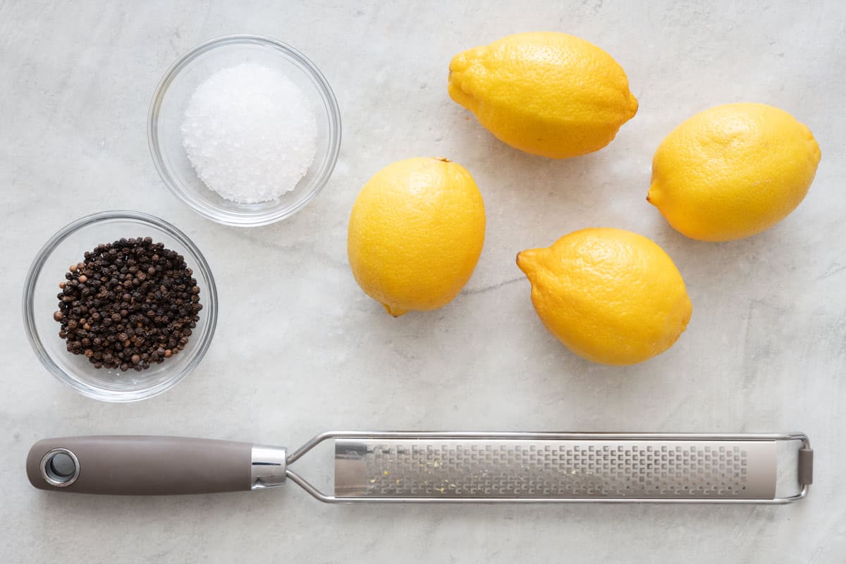 Ingredients for seasoning recipe: whole peppercorns, salt, 4 lemons, with a microplane grater.