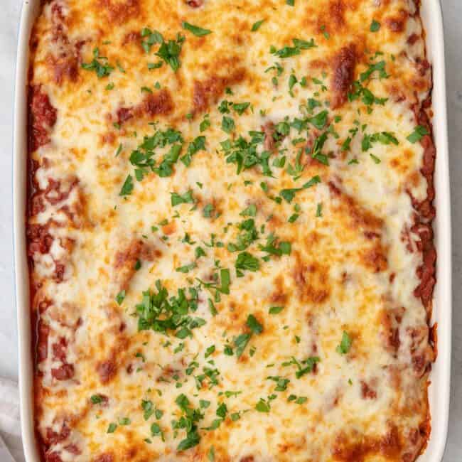 Baked macarona bechamel with browned cheese with fresh herb garnish.