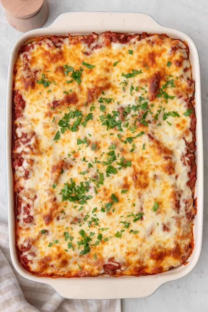 Baked macarona bechamel with browned cheese with fresh herb garnish.