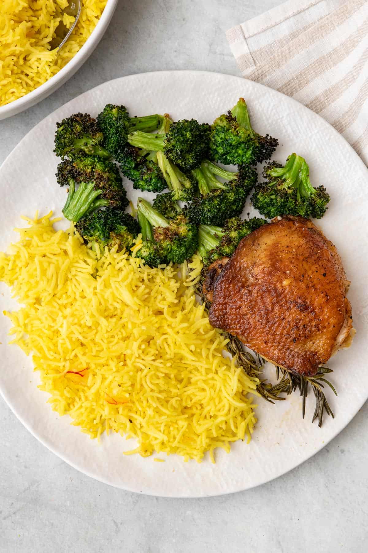 Serving plate with rosemary chicken, saffron rice, and broccoli.