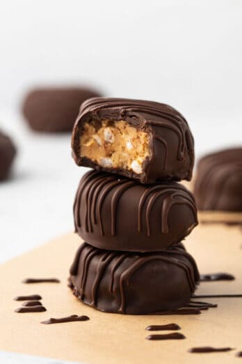 3 peanut butter eggs with chocolate coating stacked on top of each other with a bite taken out of the top egg.