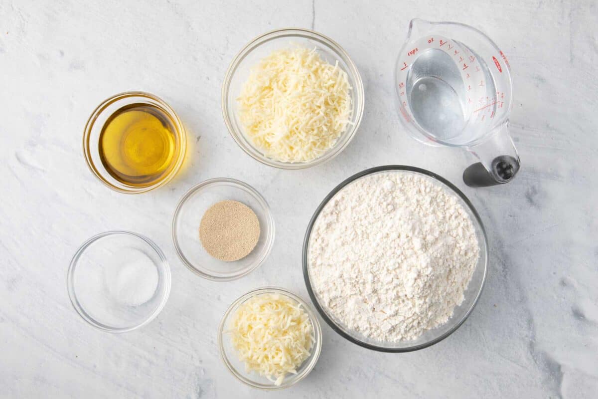 Ingredients for recipe before prepping: oil, salt, instant yeast, 2 different shredded cheeses, flour, and water.
