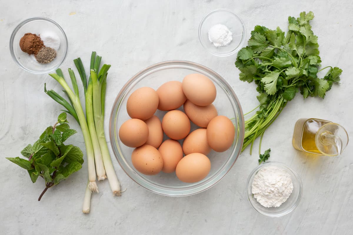 Ingredients for recipe: eggs, green onions, mint, parsley, seasonings, flour, baking powder, and oil.