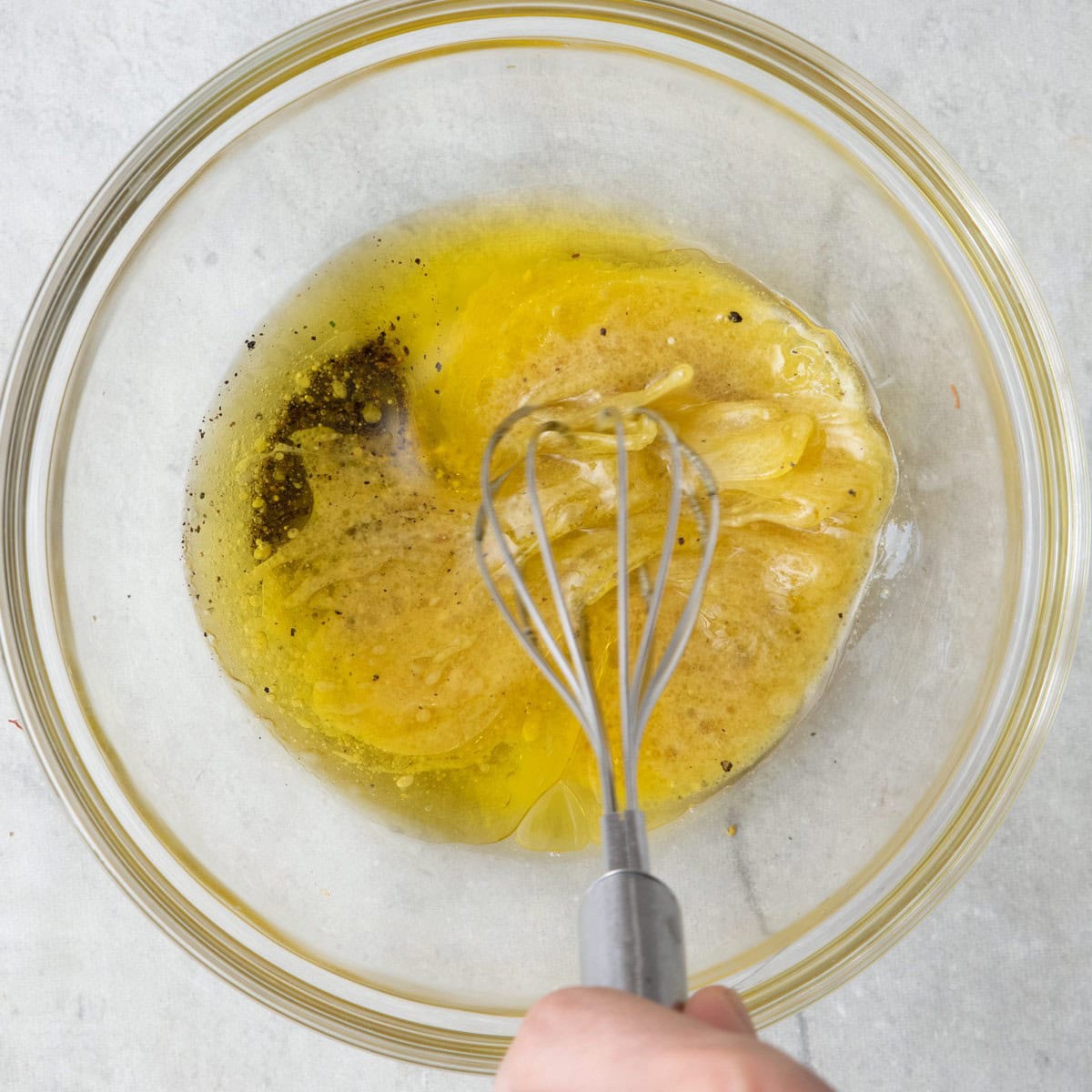Dressing ingredients in a small bowl being whisked together.