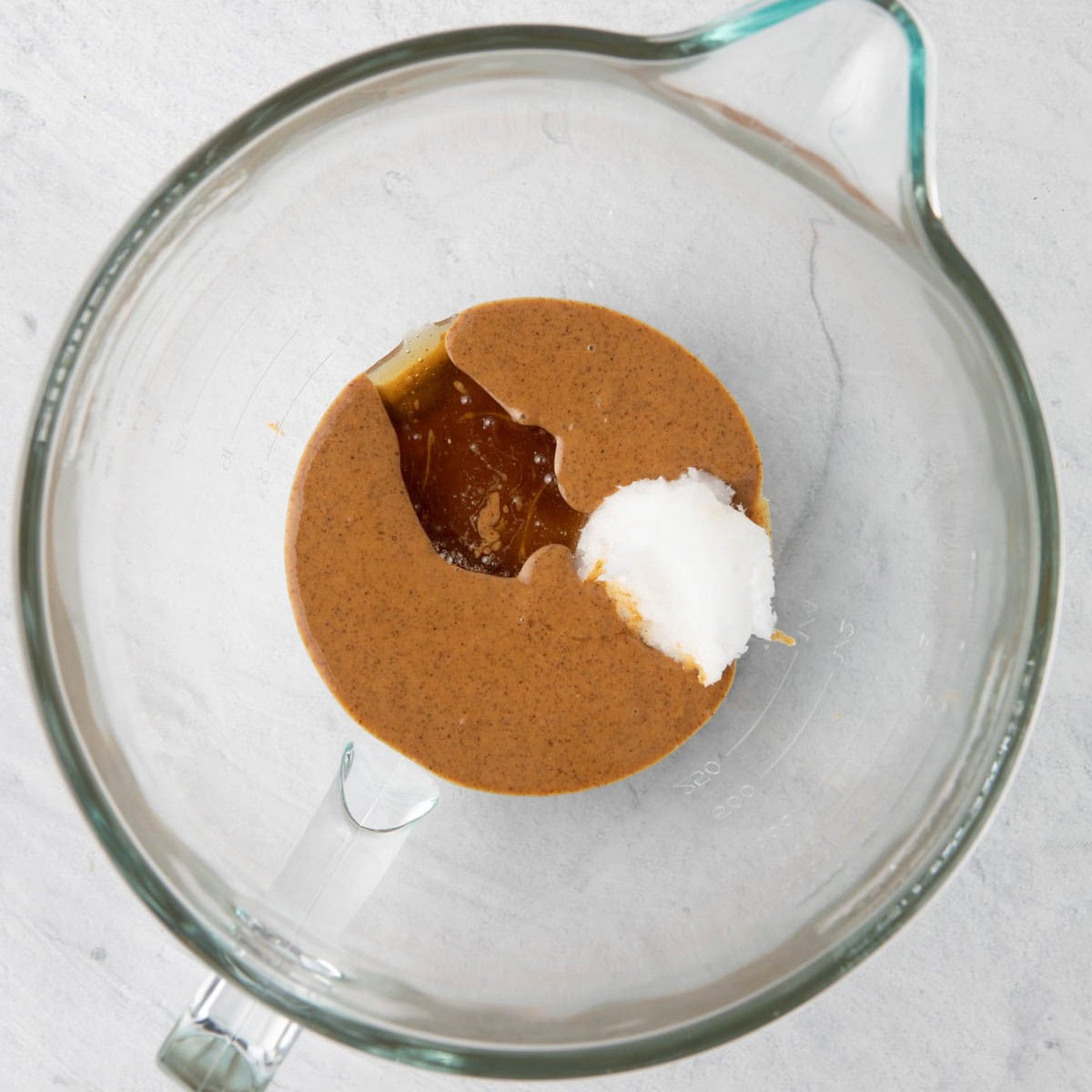 Almond butter, honey and oil in a bowl of a stand mixer before combined.
