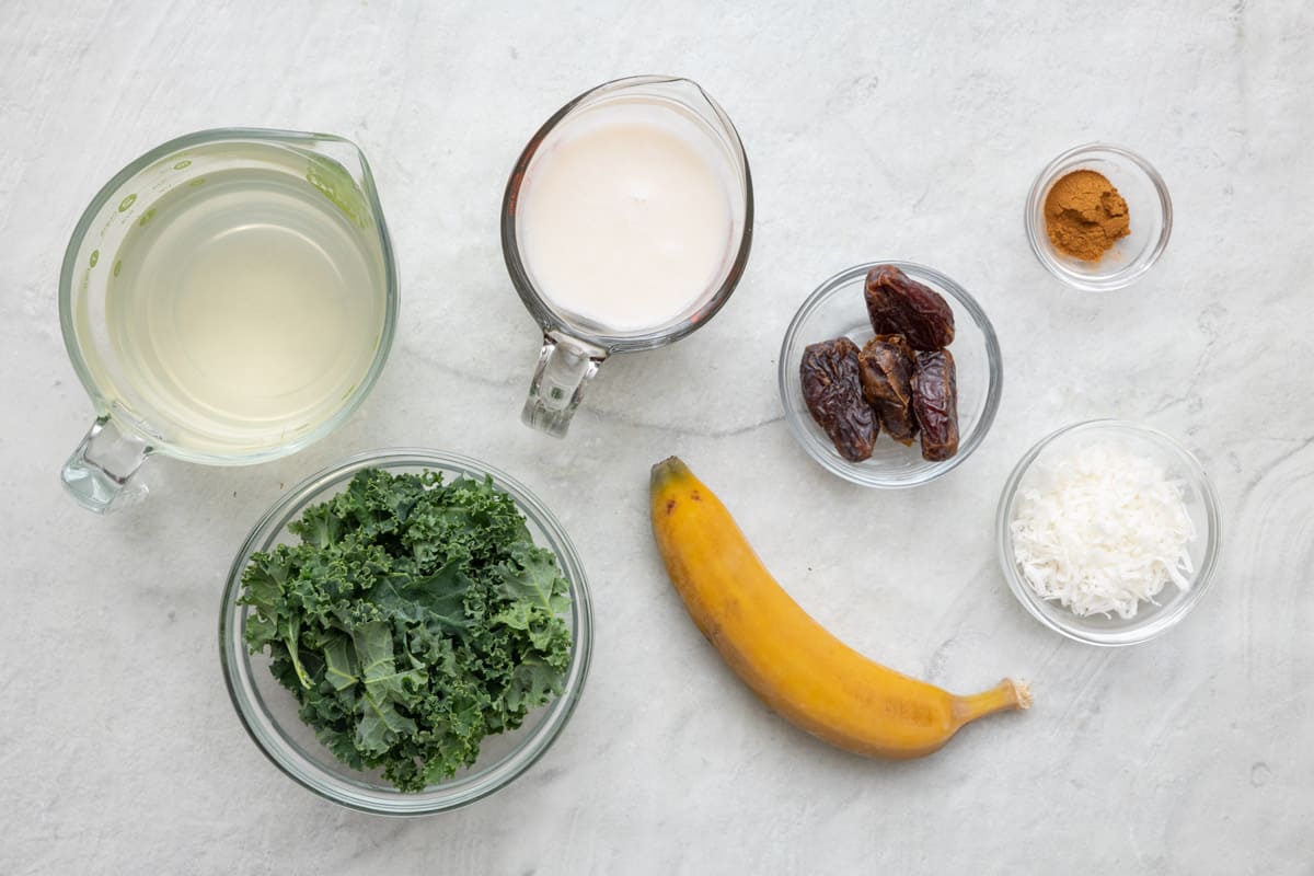 Ingredients for recipe: coconut water, almond milk, kale, banana, dates, shredded coconut, and cinnamon.