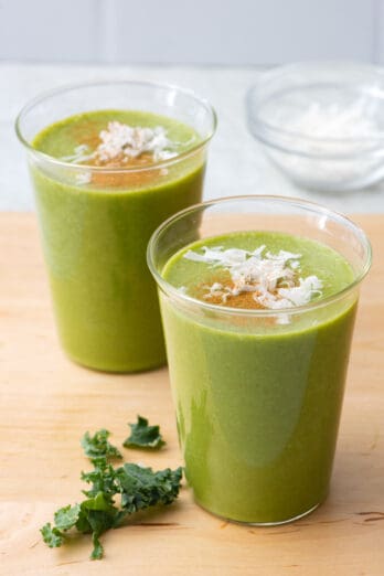 2 glasses filled with coconut kale smoothie, garnished with cinnamon and shredded coconut.