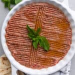 Round ceramic dish with Kebbeh Nayyeh pressed inside with decorative groves pressed into the raw beef mixture.