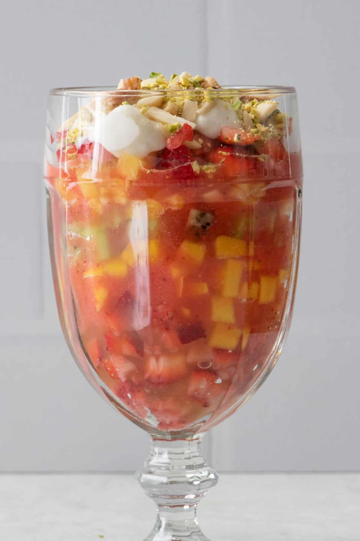 Close up of Fruit Cocktail to show the layers of fruit in juice and the ashta topping with nuts.
