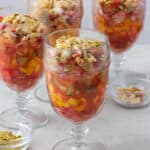 4 glasses of fruit cocktail, staggered, garnished with ashta on top and nuts sprinkled