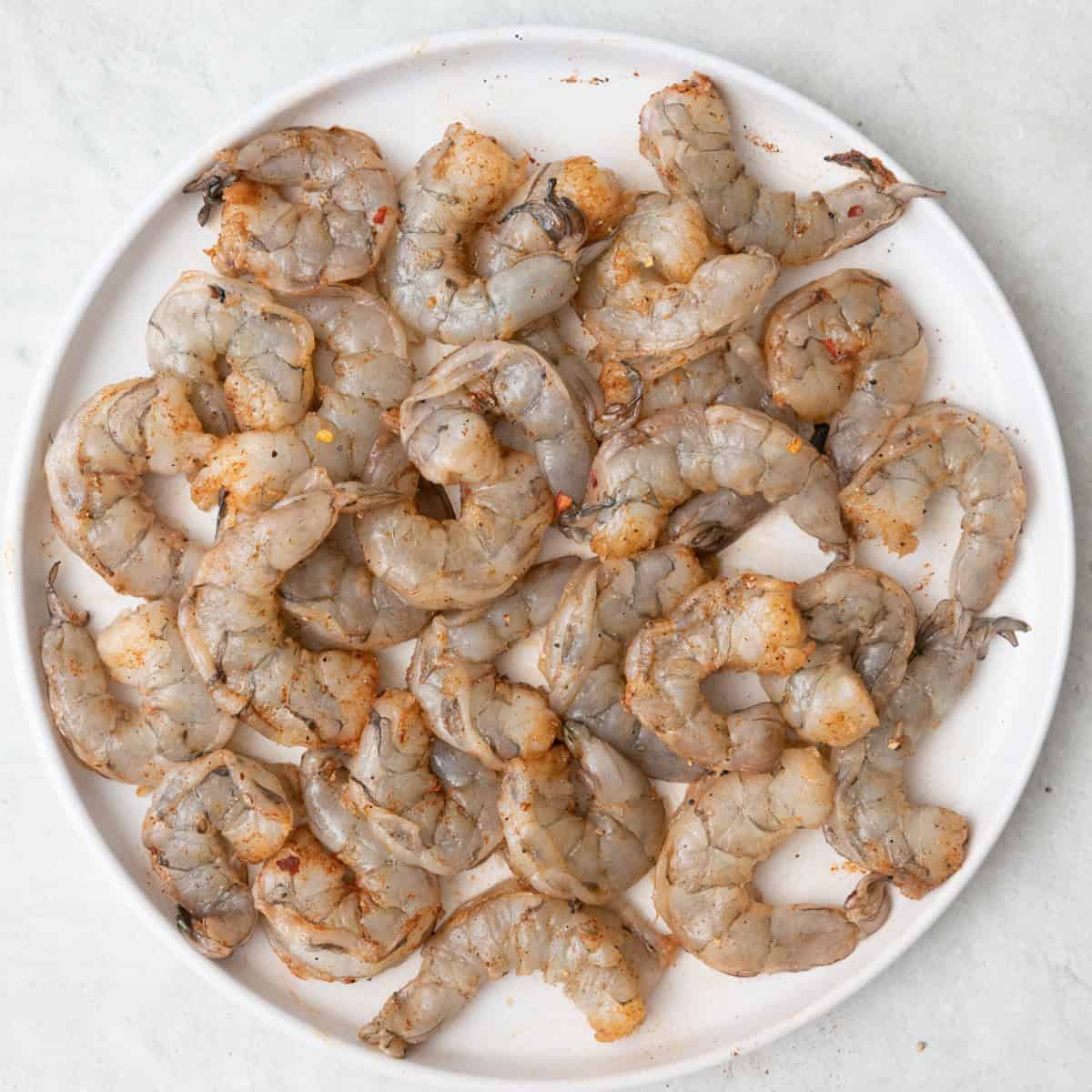 Shrimp on plate with salt, pepper, and paprika added.
