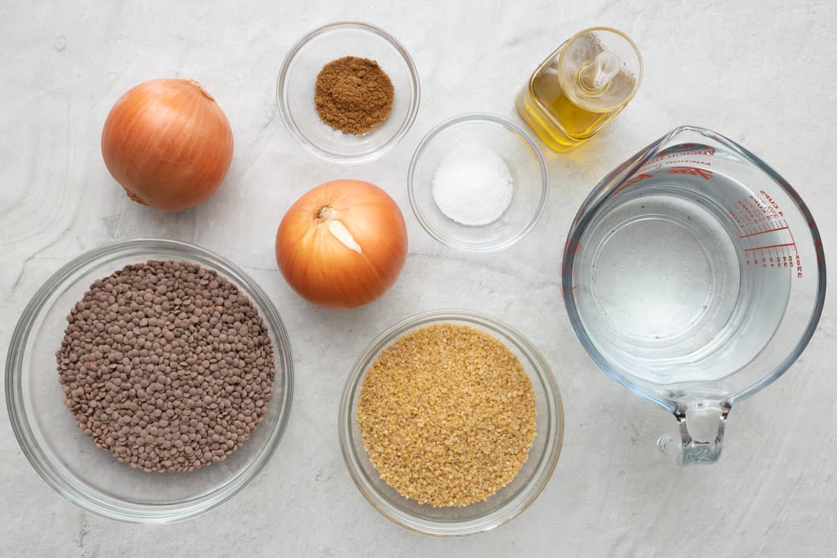 Ingredients for recipe before prepping in individual bowls or cups: red lentils, 2 yellow onions, coarse bulgur, cumin, salt, oil, and water.