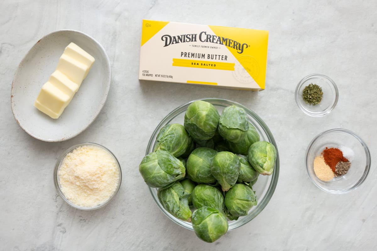 Ingredients for recipe before prepping: fresh brussel sprouts, parmesan cheese, Danish Creamery Premium Sea Salted Butter box with some cut into slices, and seasonings.