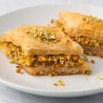 Plate with 2 pieces of baklava showing the thick pistachio layer and flaky layers.