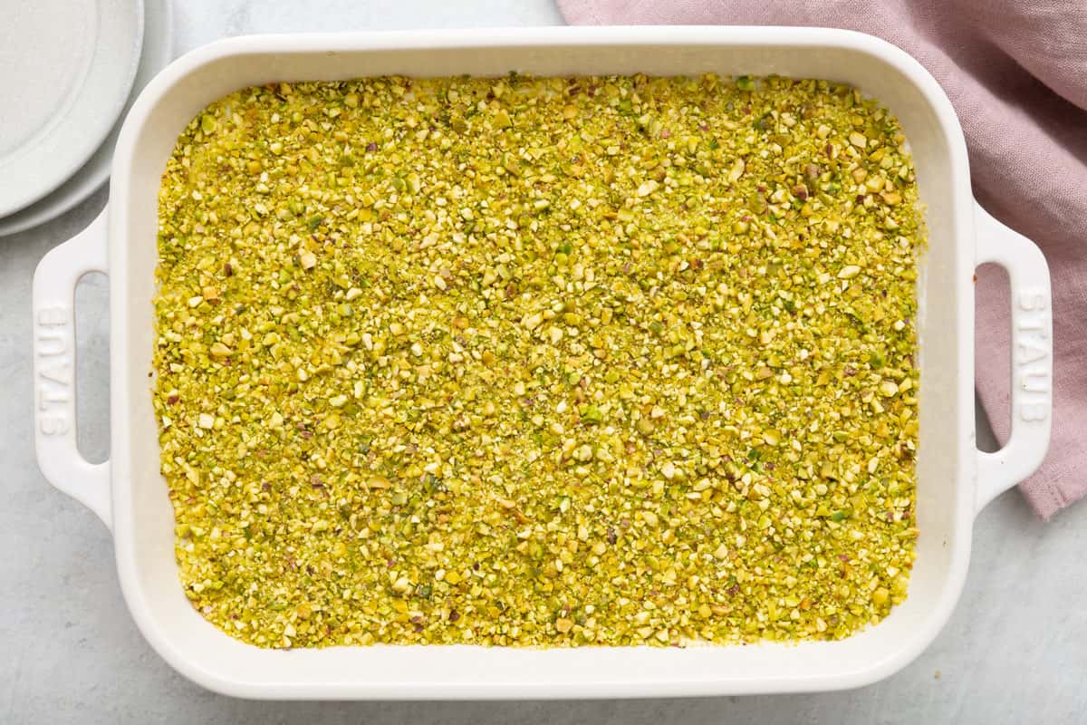 Semolina Pudding with ashta in baking dish garnished with finely chopped pistachios.