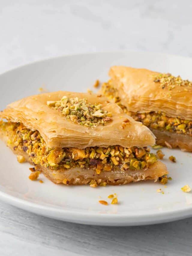 Plate with 2 pieces of baklava showing the thick pistachio layer and flaky layers.