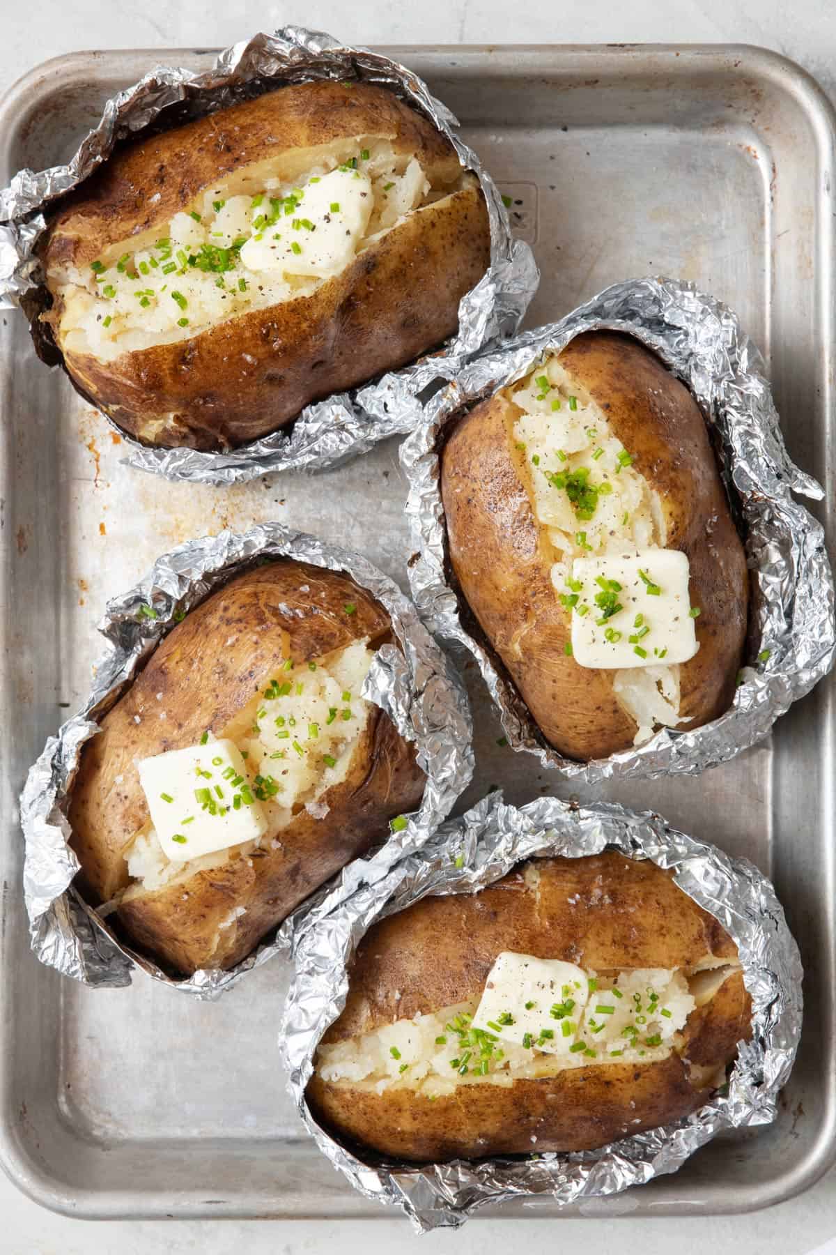 4 baked potatoes in foil split open and fluffed with a pat on butter on each and garnished with chopped chives and salt.