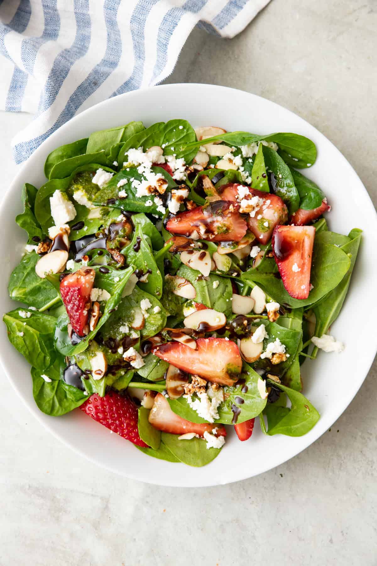 Fresh spinach salad with balsamic glaze drizzled on top.