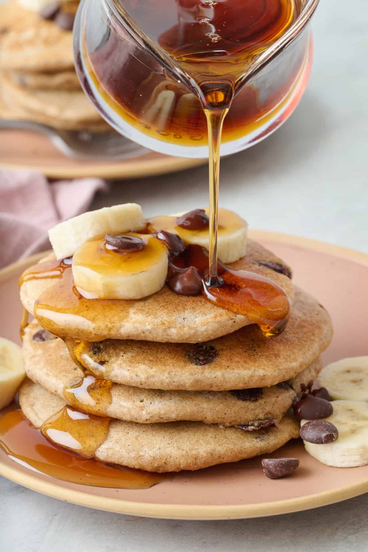 Maple syrup getting poured on oat flour pancakes stake