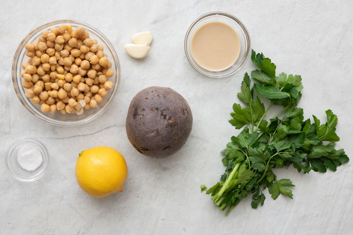 Ingredients for recipe: chickpeas, salt, garlic, lemon, a beet, tahini, and fresh parsley.