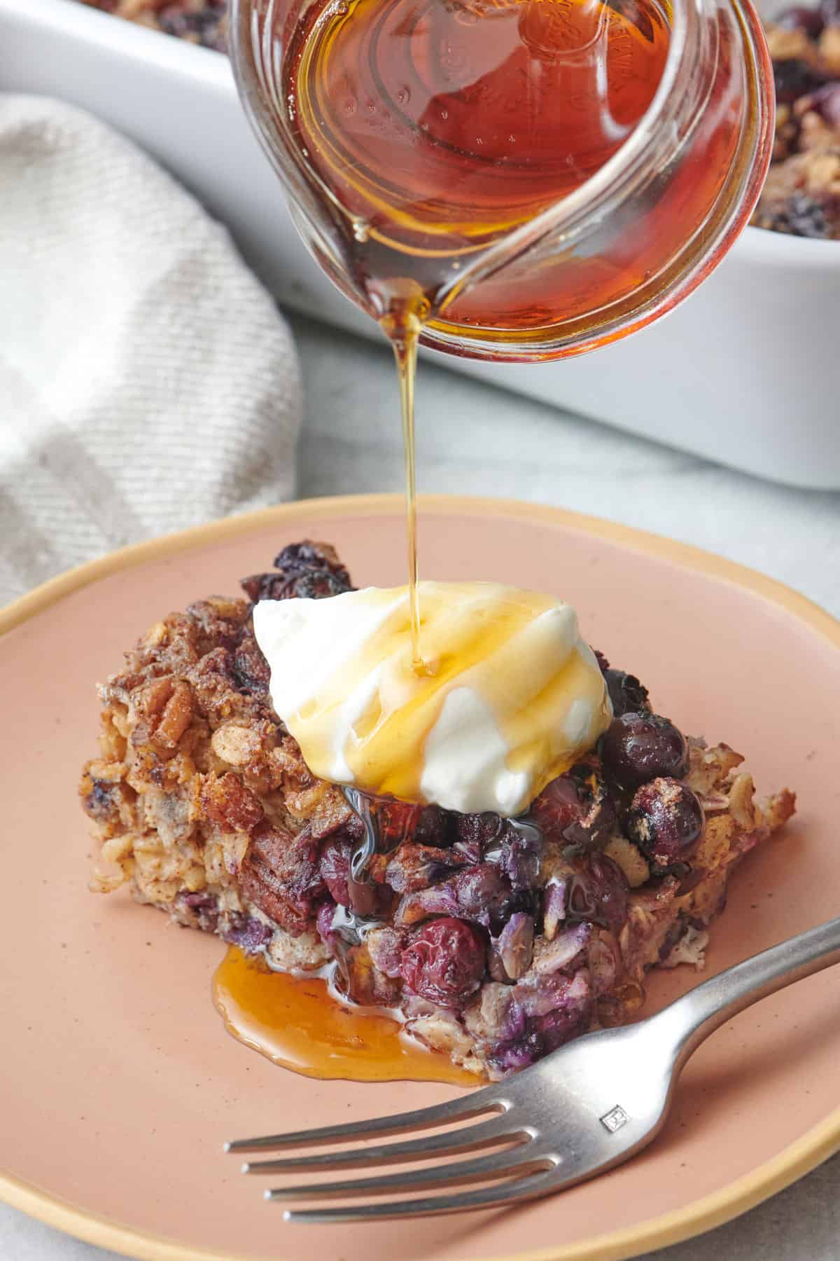 Slice of baked blueberry oatmeal with greek yogurt on top and fork