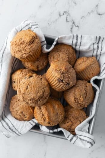 Whole wheat bran muffins in a clothed lined pan for serving.