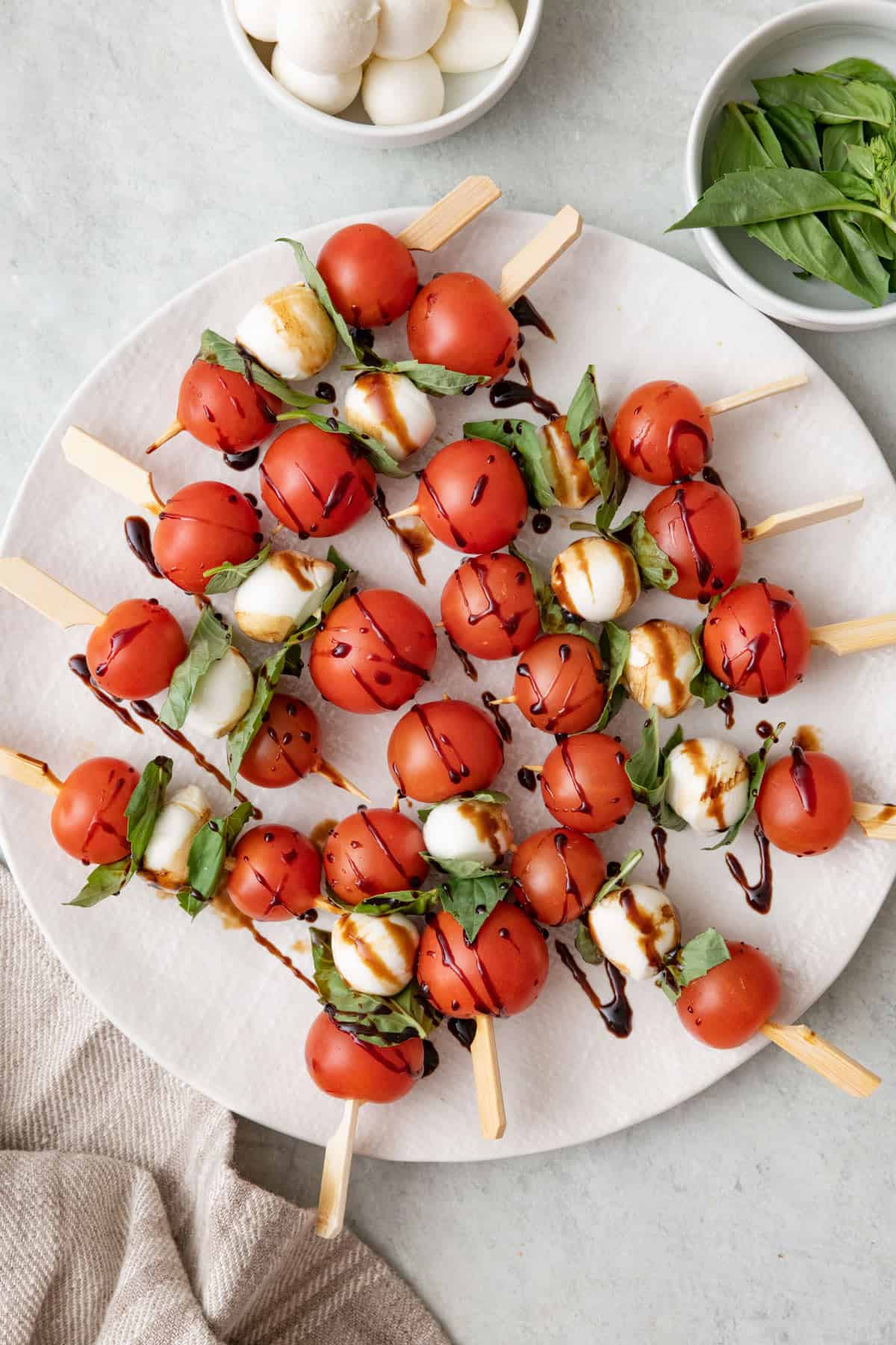 Caprese skewers on a large round plate with balsamic glazed drizzled ...