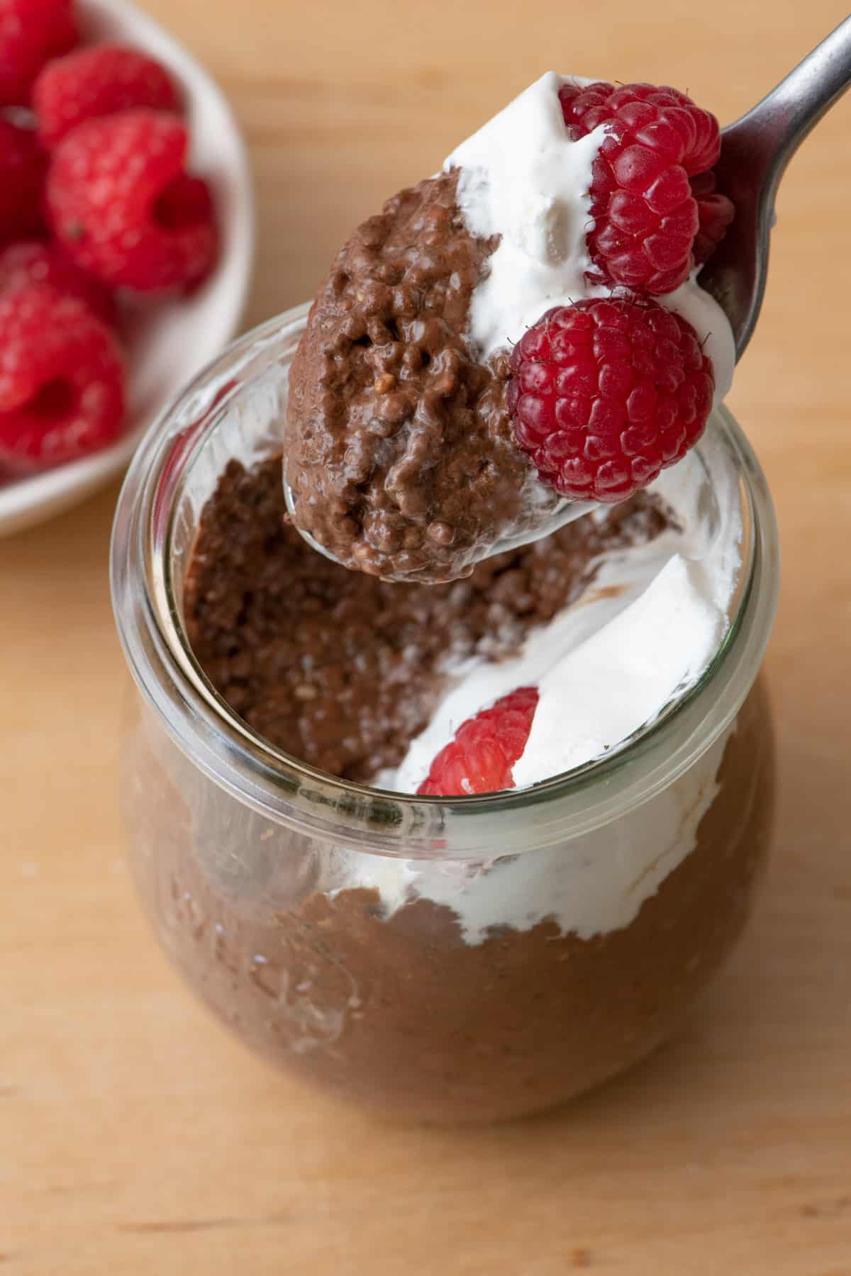 Top view of chocolate chia pudding in glass jars with bite taken out of one of them