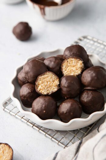 Plate of chocolate coconut balls with one cut in half to show inside texture.