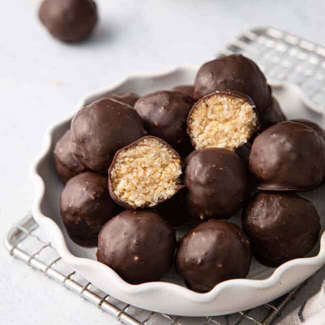 Plate of chocolate coconut balls with one cut in half to show inside texture.