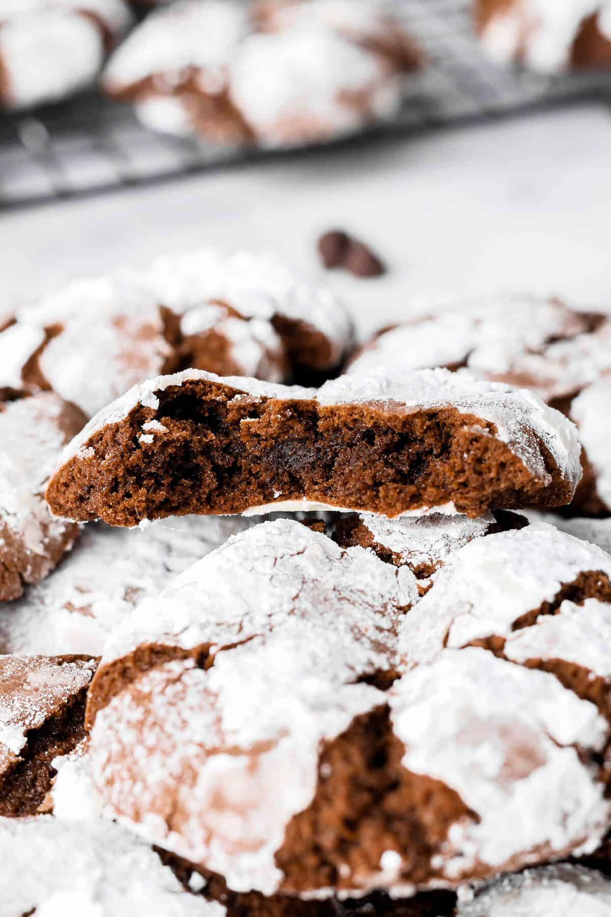 Close up of a chocolate crinkle cookie with a bite taken out to show the inside texture.