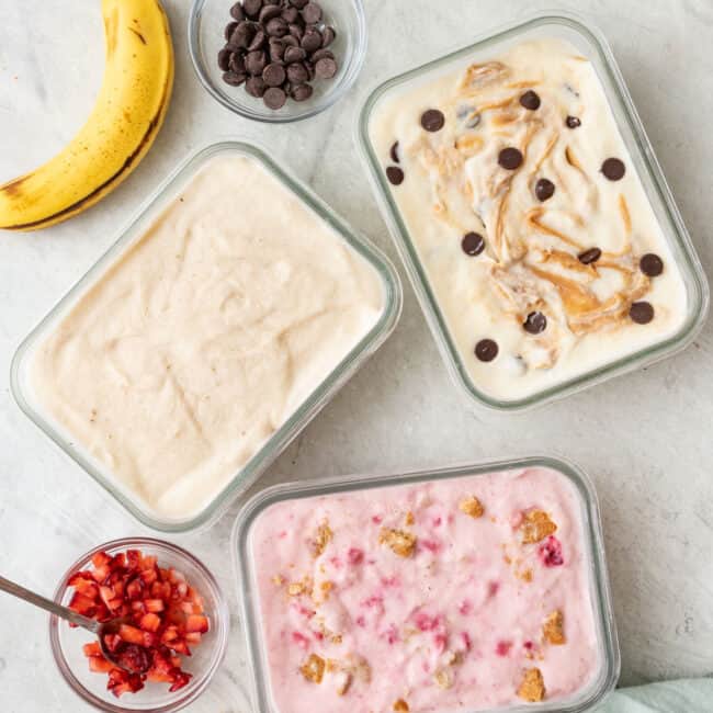 Cottage cheese icecrea in glass containers made with 3 different flavors: peanut butter chocolate chip, banana cream, and strawberry cheesecake. Extra toppings nearby.
