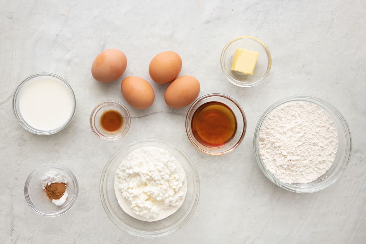 Ingredients for recipe: milk, baking powder, cinnamon, salt, vanilla, 4 eggs, cottage cheese, maple syrup, butter, and flour.