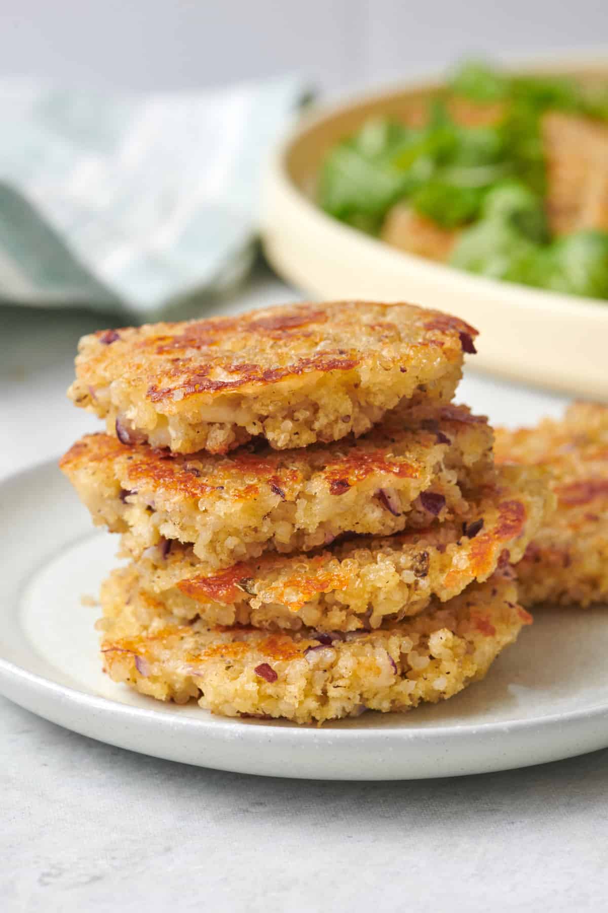 Quinoa patties stacked up on a small plate to show crispy crust.