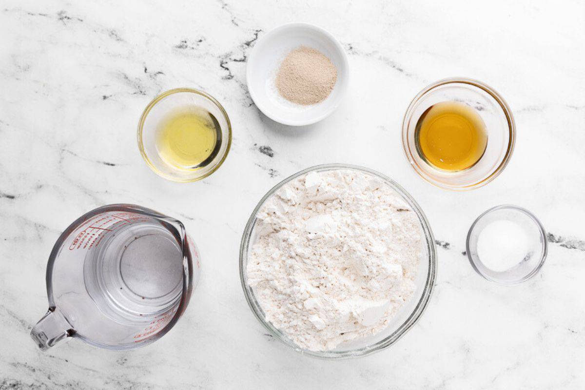 Ingredients for recipe in individual dishes: hot water, oil, yeast, flour, honey, and salt.
