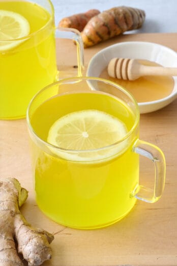 Ginger tea with lemon and honey in two glass mugs.