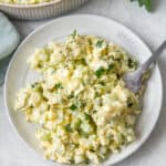Healthy Egg Salad a a small plate with a fork resting on it, serving bowl nearby.