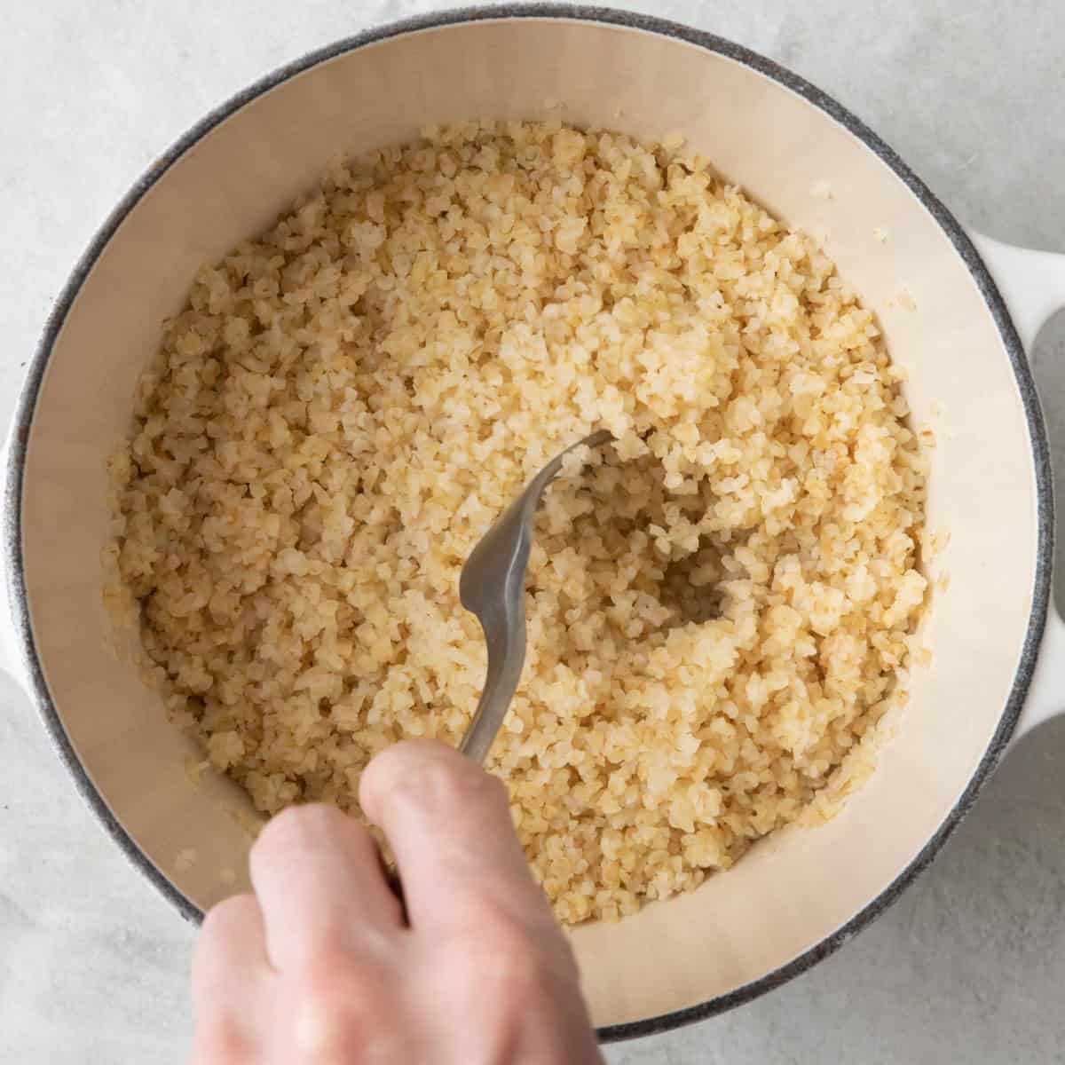 Fluffing bulgur with a fork.