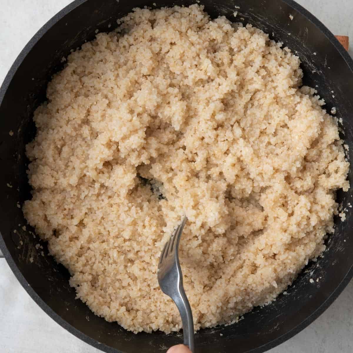 Fluffing bulgur with a fork.