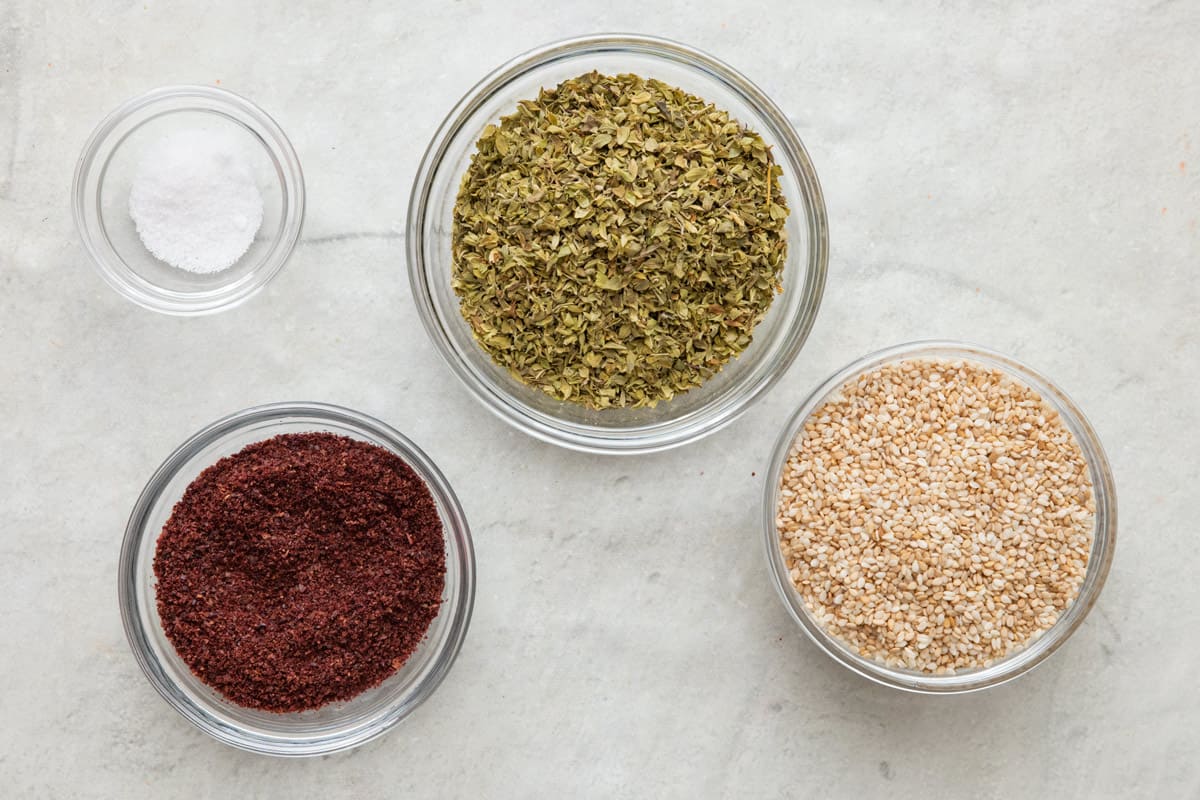 Ingredients for spice blend: fine salt, sumac, oregano, and toasted sesame seeds.