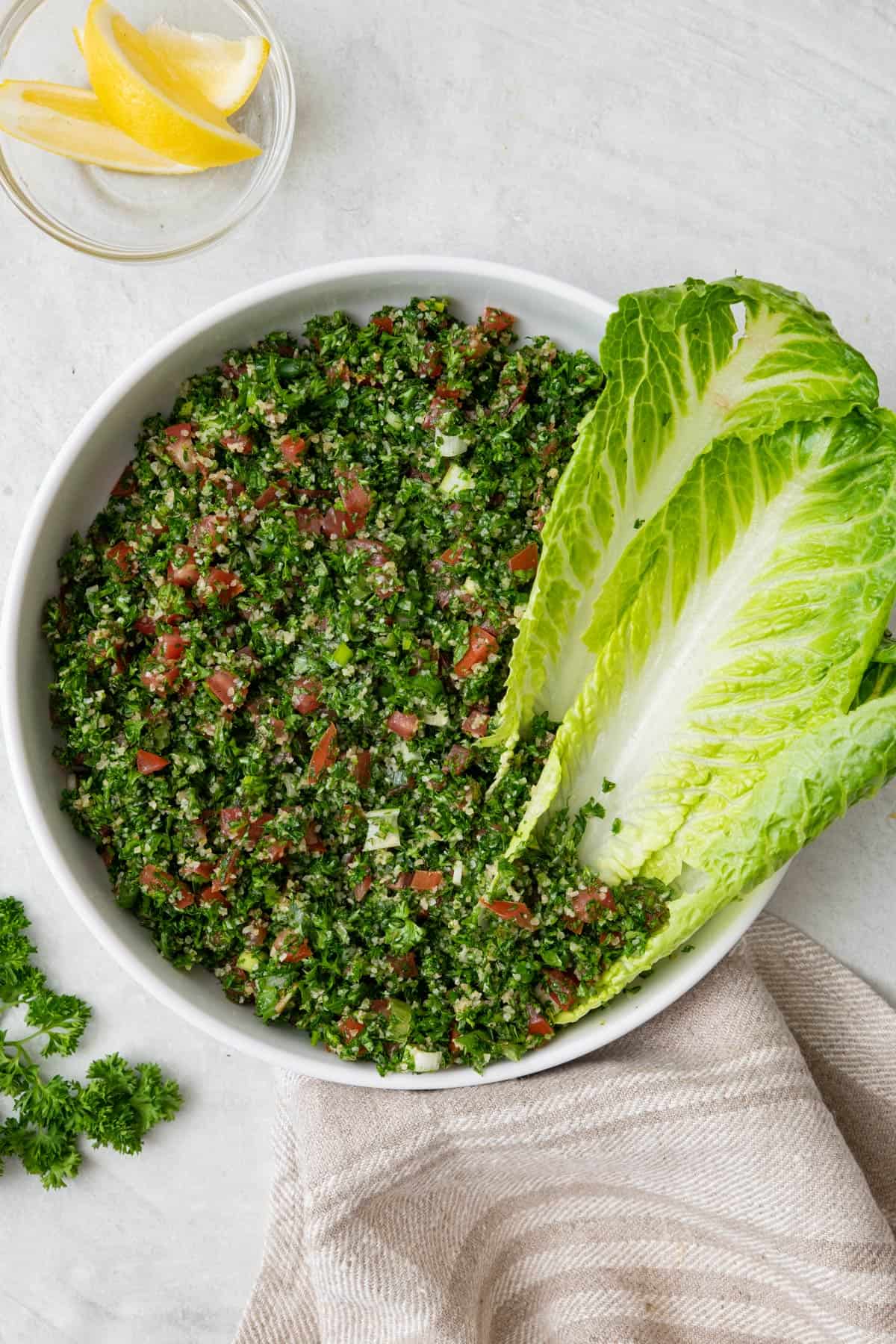 Bowl of Lebanese tabbouleh salad with romaine lettuce leaves tucked inside bowl for serving.